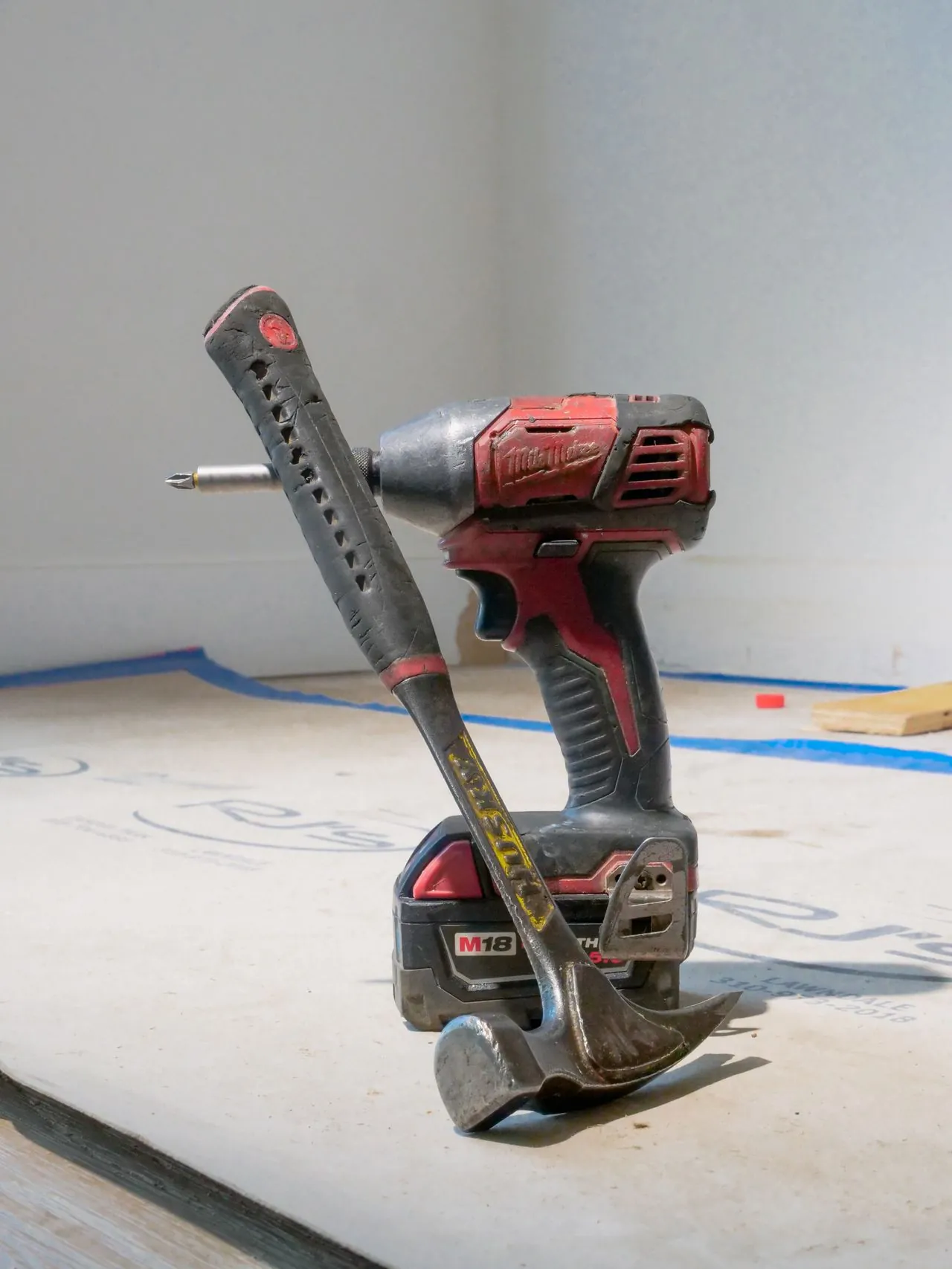 Cordless drill and hammer on a job site floor