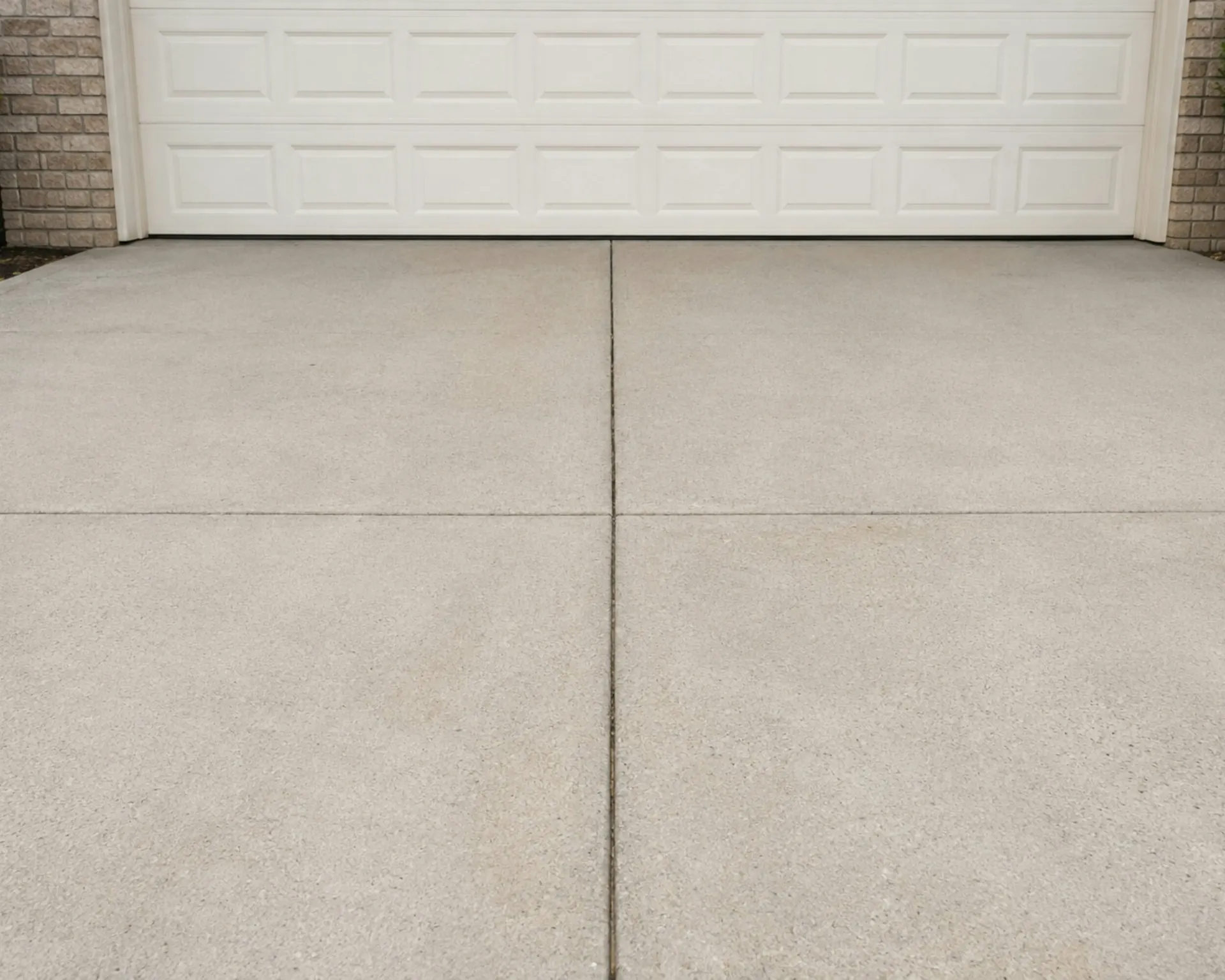 White sectional garage door at the top of a concrete driveway